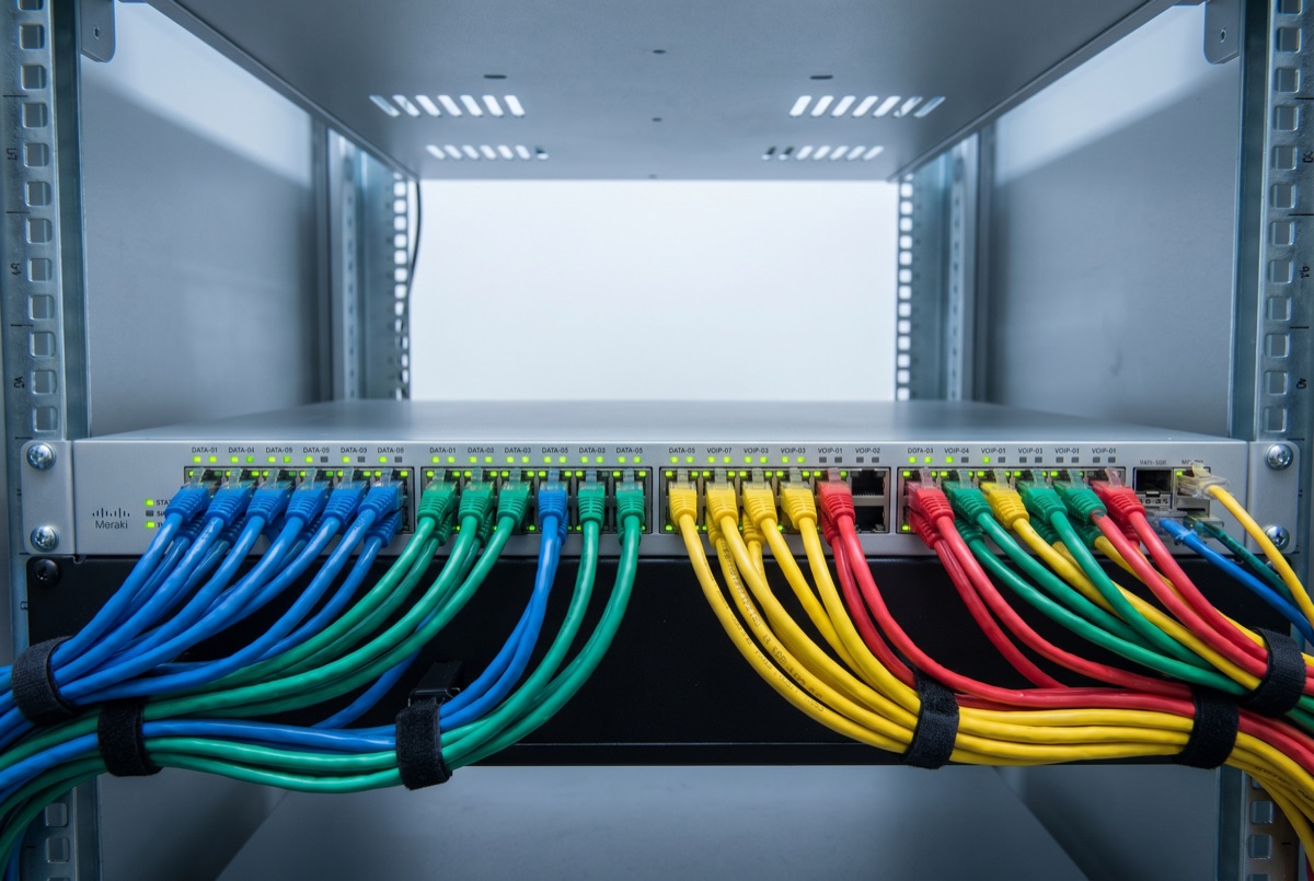 Cisco Meraki switch mounted in a rack with colour-coded patch leads